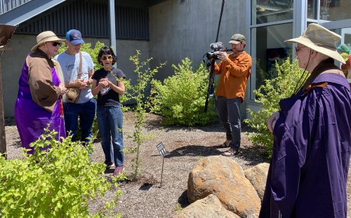Multiple peopl stand behind on of the Ginkgo trees with camera operator in the background